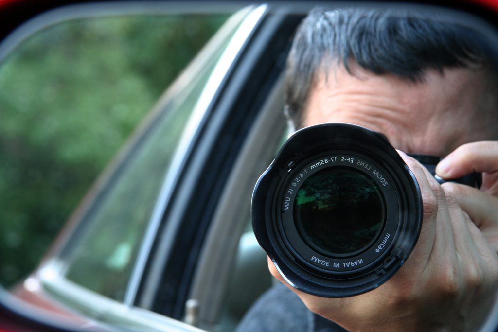 A professional investigator conducting discreet field surveillance from a vehicle